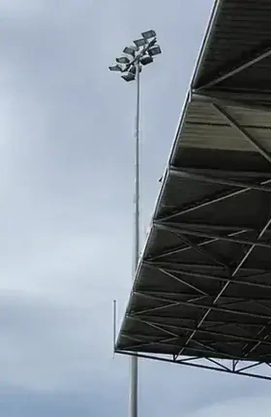 Sports lighting beside a grandstand roof.